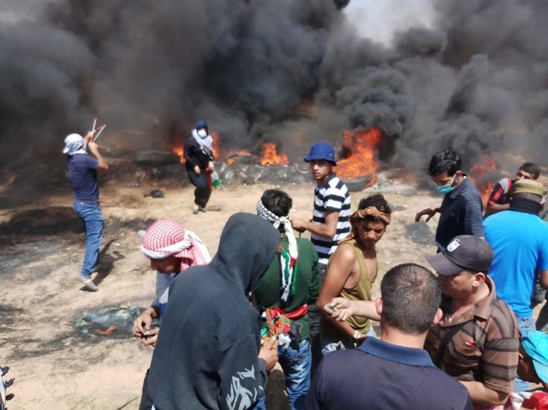 فلسطيني يحمل مصابا خلال الاشتباكات مع قوات الاحتلال