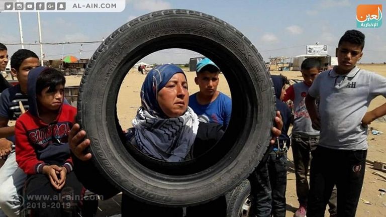 سيدة فلسطينية ترفع إطار سيارة للمشاركة في جمعة النذير