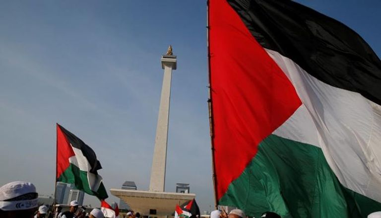 المتظاهرون في حديقة النصب التذكاري ملوحون بالأعلام الفلسطينية - رويترز