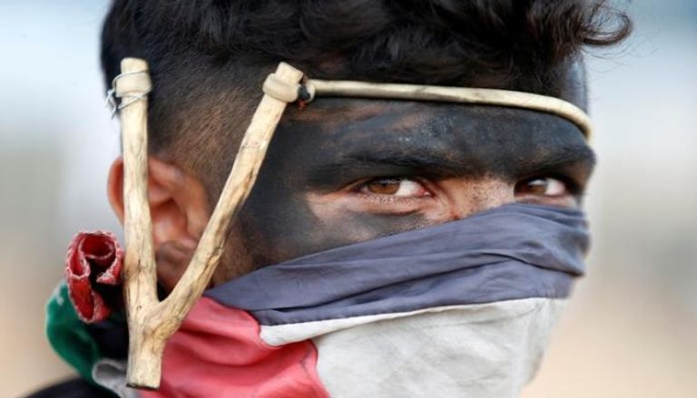 متظاهر فلسطيني سلمي يحمل مقلاعا في وجه الاحتلال-رويترز 