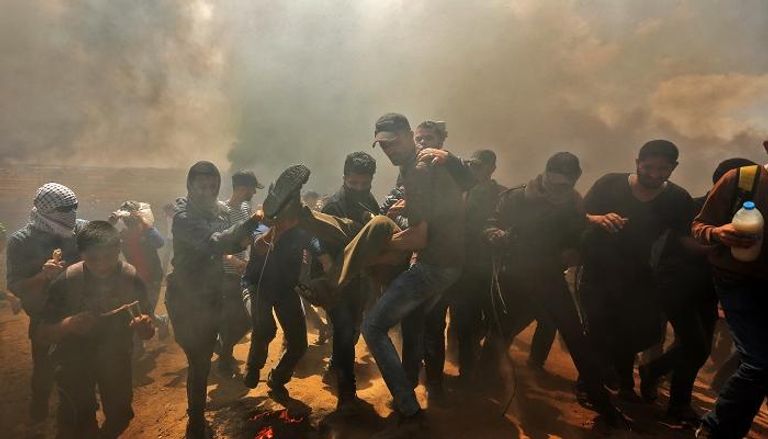 شبان يحملون جريحا فلسطينيا سقط خلال المواجهات مع الاحتلال