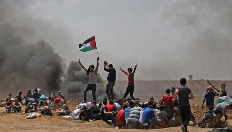 شباب فلسطيني يرفع العلم أثناء احتجاجات ذكري النكبة