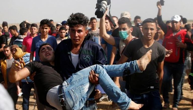 فلسطيني يحمل مصابا خلال الاشتباكات مع قوات الاحتلال