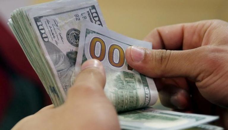 مصري يمسك بعملات ورقية من فئة 100 دولار في بنك القاهرة