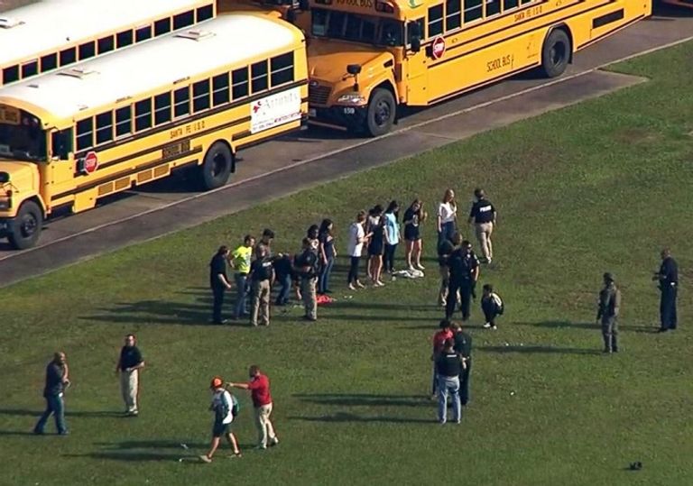 الشرطة مع بعض الطلبة أمام المدرسة سيارات الإسعاف في موقع الحادث