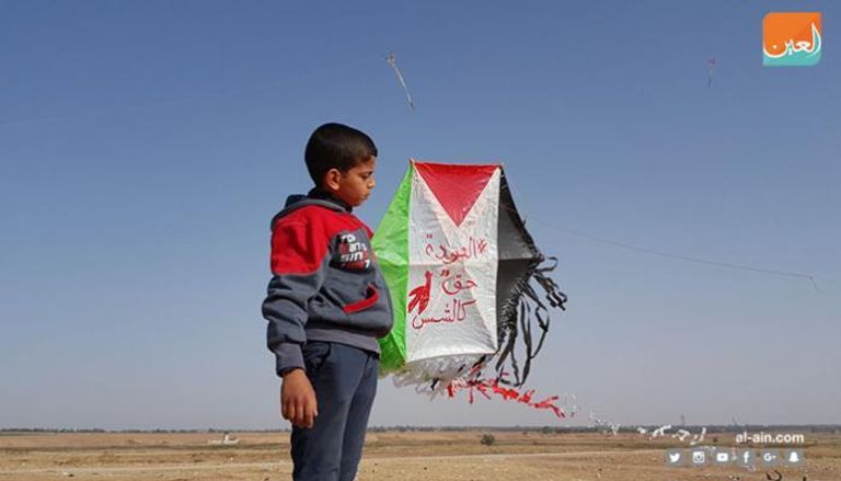 طفل يحمل طائرة ورقية عليها علم فلسطين