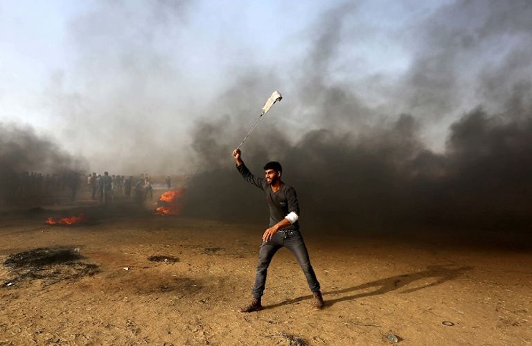 شاب فلسطيني يستخدم النقيفة لرمي قوات الاحتلال بالحجارة شاب فلسطيني يفلت حجارته تجاه قوات الاحتلال في غزة