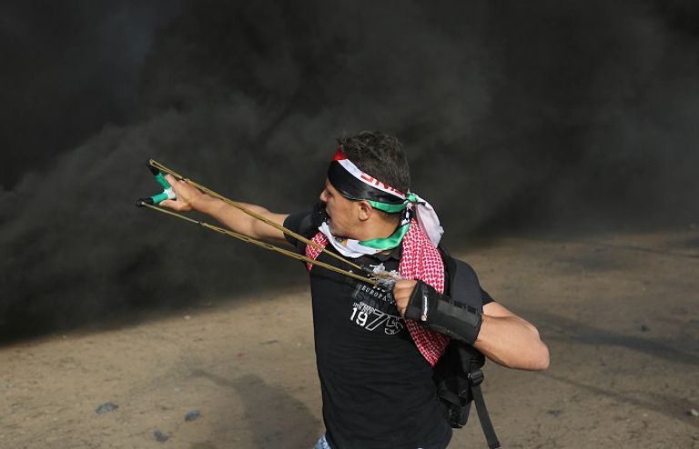 شاب فلسطيني في غزة يرمي جنود الاحتلال بالحجارة شاب فلسطيني يفلت حجارته تجاه قوات الاحتلال في غزة