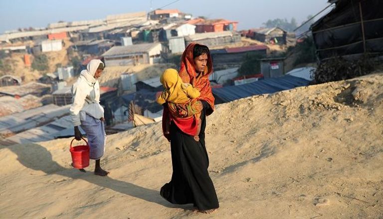 سيدة من لاجئي الروهينجا تحمل طفلتها في ظروف صعبة للغاية لاجئون من مسلمي الروهينجا في طريقهم إلى بنجلاديش