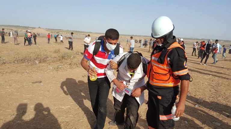 رجال الإسعاف يحملون فلسطينيا مصاب بالاختناق من الغاز مسيرات جمعة الوفاء للجرحى في غزة