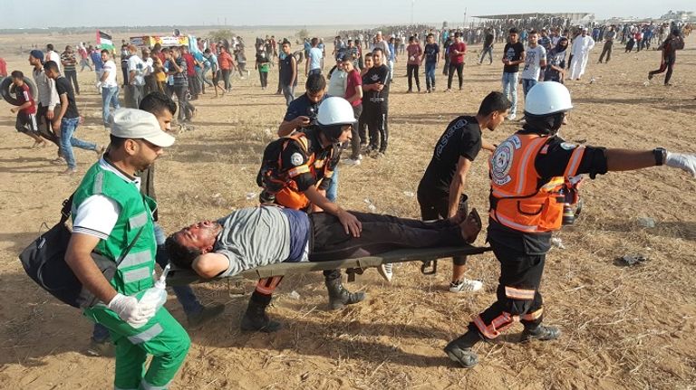 رجال الإسعاف يحملون فلسطينيا مصاب بالرصاص الحي مسيرات جمعة الوفاء للجرحى في غزة
