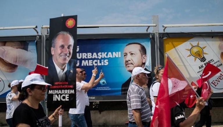 أتراك أمام ملصقات دعائية للرئيس أردوغان ومنافسه الأبرز محرم إنجه
