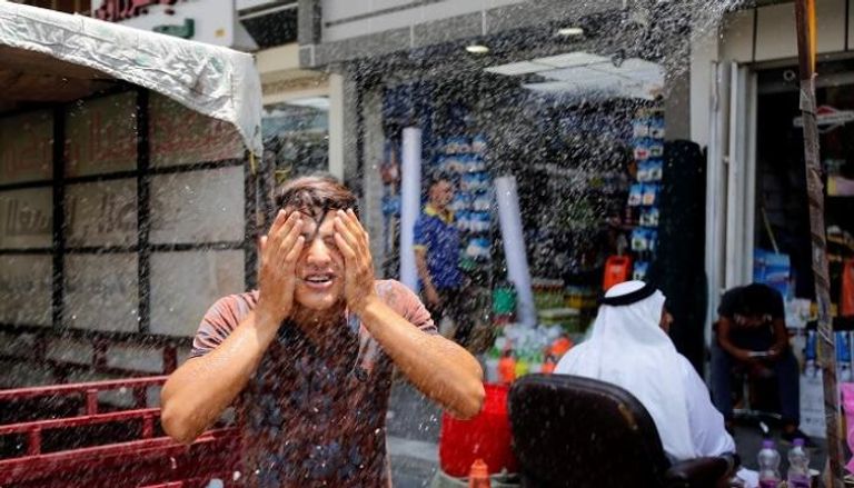 سكان بغداد يلجأون لرش المياه تخفيفاً لموجة الحر (رويترز)