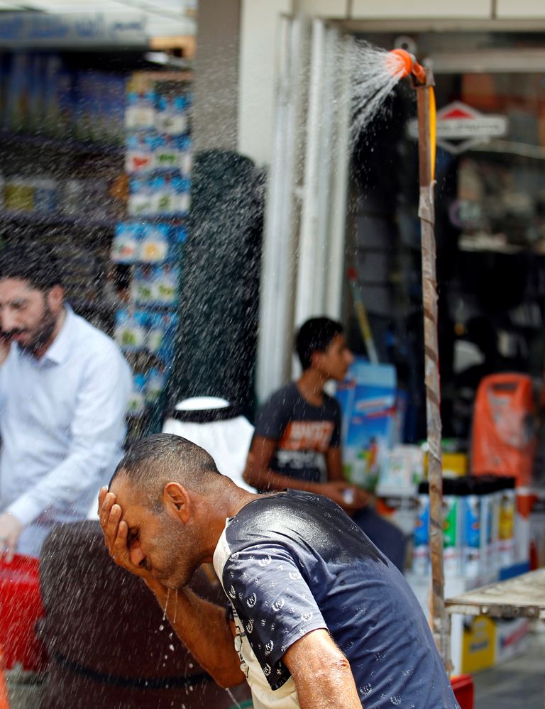 سكان بغداد يلجأون لرش المياه تخفيفاً لموجة الحر (رويترز)