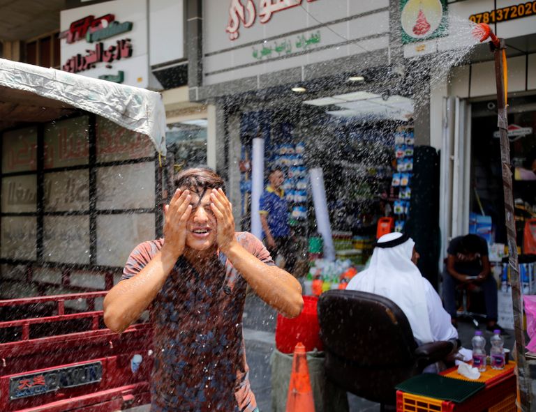 سكان بغداد يلجأون لرش المياه تخفيفاً لموجة الحر (رويترز)
