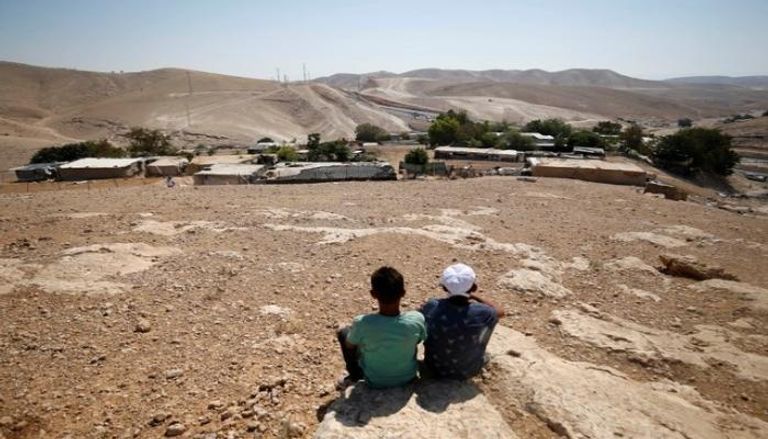 أطفال فلسطينيون يجلسون في قرية 