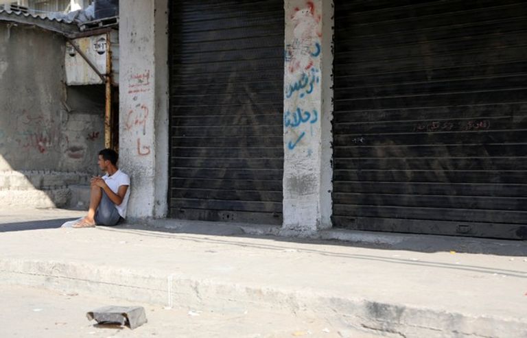 فلسطيني يجلس أمام محل تجاري في مخيم الشاطئ بغزة-رويترز طفل فلسطيني يبكي شقيقه الذي استشهد بنيران الاحتلال