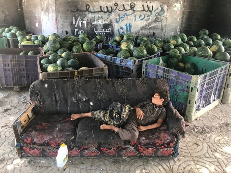 طفل فلسطيني ينام على أريكة في محل لبيع البطيخ بغزة-رويترز طفل فلسطيني يبكي شقيقه الذي استشهد بنيران الاحتلال