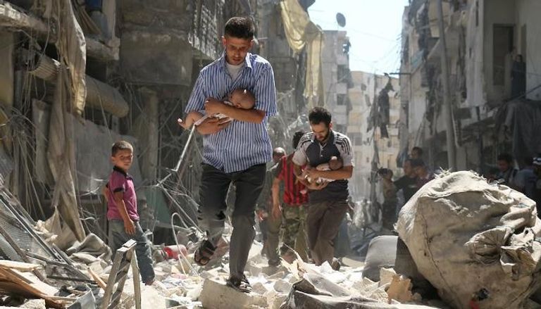 سوريون يحملون أطفالا بعد غارة جوية في حلب