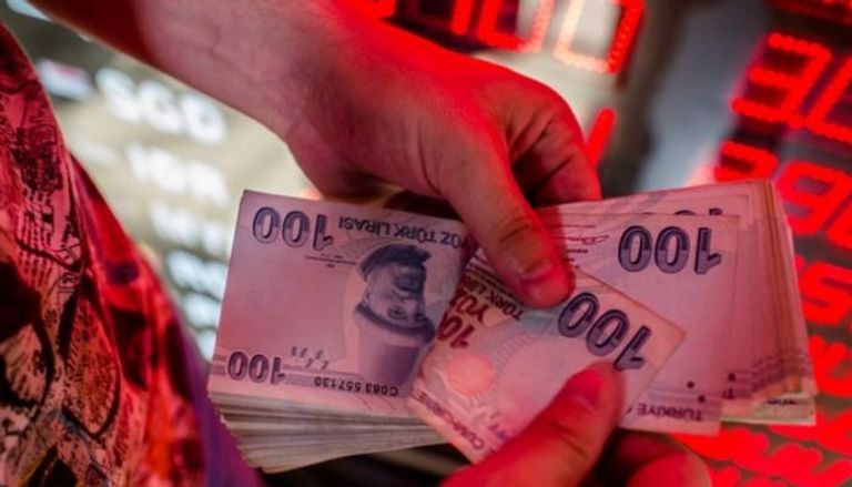 موظف يمسك بأوراق نقدية من الليرة في مكتب صرافة بإسطنبول