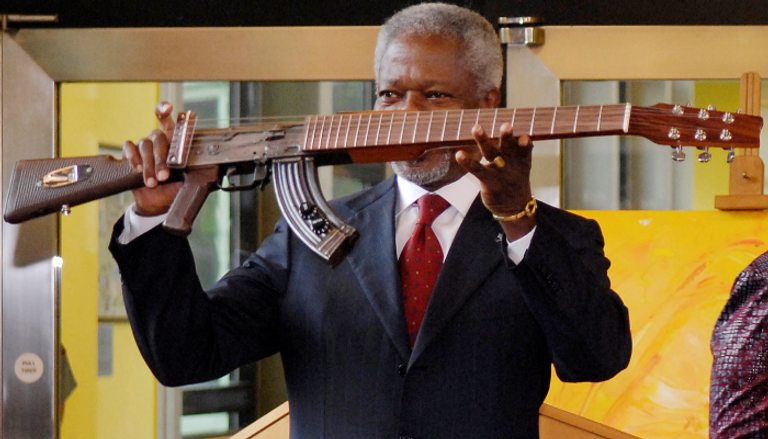 كوفي عنان يحمل سلاحا آليا تم تعديله ليصبح آلة موسيقية كرمز للسلام