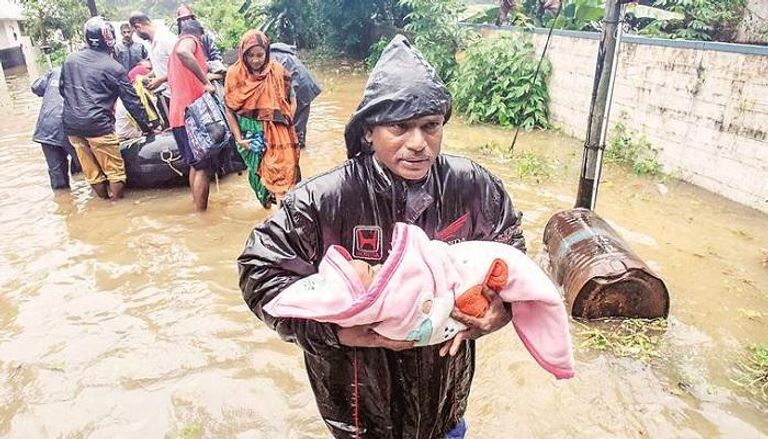 أحد المتضررين من فيضان كيرلا يحمل طفله وسط المياه