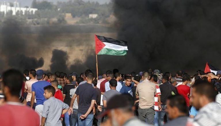 العلم الفلسطيني مرفوع خلال حشد من الفلسطينيين أثناء مسيرات العودة