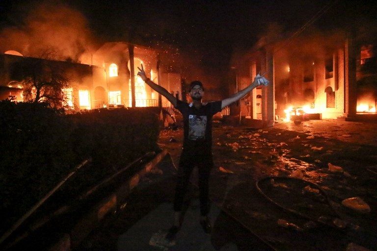 النيران تلتهم القنصلية الإيرانية في البصرة شاب عراقي يحرق العلم الإيراني خلال مظاهرات البصرة - أ.ف.ب