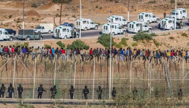 مهاجرون يعبرون السياج الحدودي بين المغرب وإسبانيا