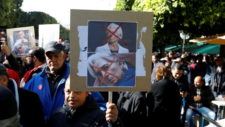 متظاهرون تونسيون يرقعون صورا لرئيسة صندوق النقد الدولي كريستين لاغارد مشطوبة بعلامة حمراء متظاهرون يحملون علم اتحاد الشغل التونسي - رويترز