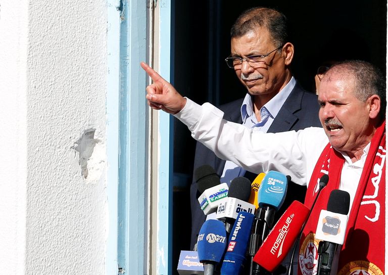 نور الدين الطبوبي الأمين العام لاتحاد الشغل التونسي - رويترز متظاهرون يحملون علم اتحاد الشغل التونسي - رويترز