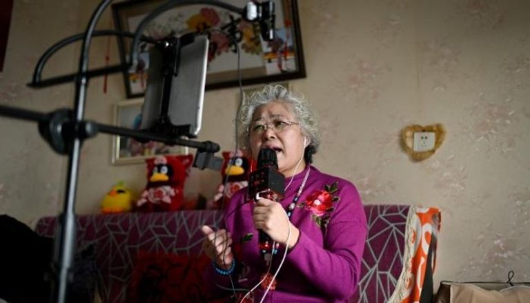 مسنة صينية تستخدم هاتفها الذكي خلال الغناء