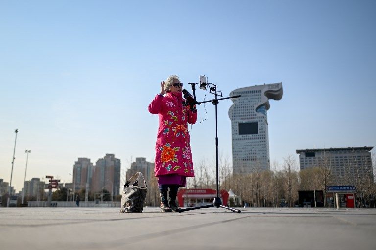 مسنة صينية تستخدم هاتفها الذكي خلال الغناء