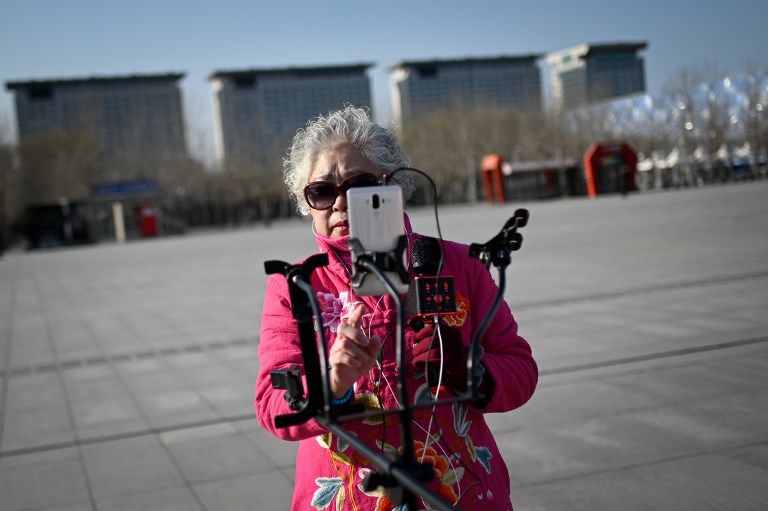 مسنة صينية تستخدم هاتفها الذكي خلال الغناء