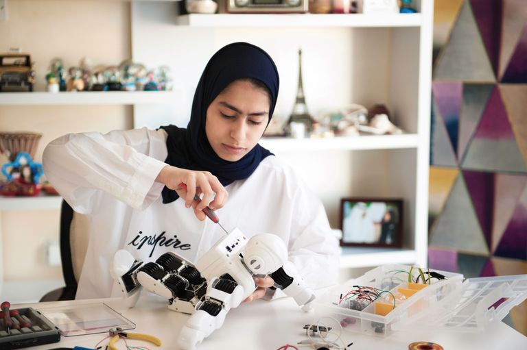 الطالبة فاطمة الكعبي تجري تجاربها على روبوت