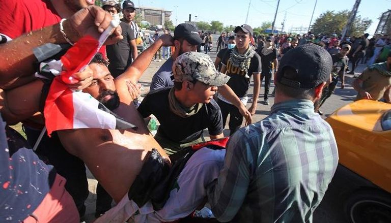 المتظاهرون يحملون أحد المصابين في العراق