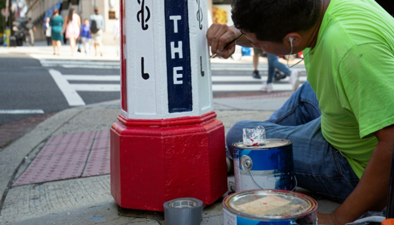 فنان يزين أحد صناديق هواتف الطوارئ في واشنطن