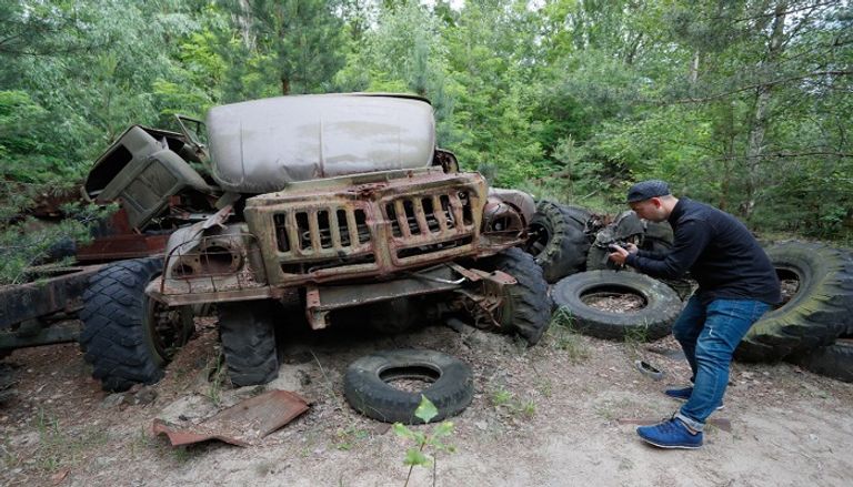 زائر يلتقط صورة لحافلة مهملة خلال جولة في تشرنوبل بأوكرانيا في السابع من يونيو/تموز من عام 2019. إحدى المناطق المهجورة في تشرنوبل