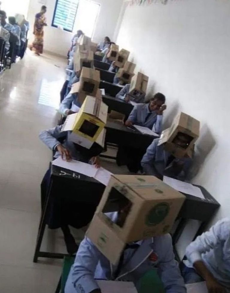 طلاب يضعون صناديق فوق رؤوسهم خلال أداء الامتحان