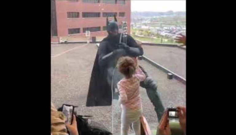 ضابط الشرطة المتنكر في زي باتمان يلوح للأطفال
