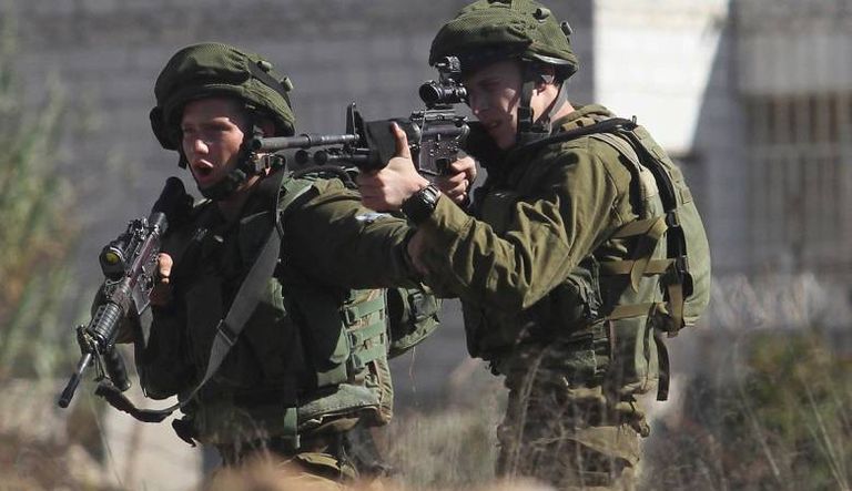 جنود الاحتلال يصوبون أسلحتهم تجاه محتجين فلسطينيين - أرشيفية