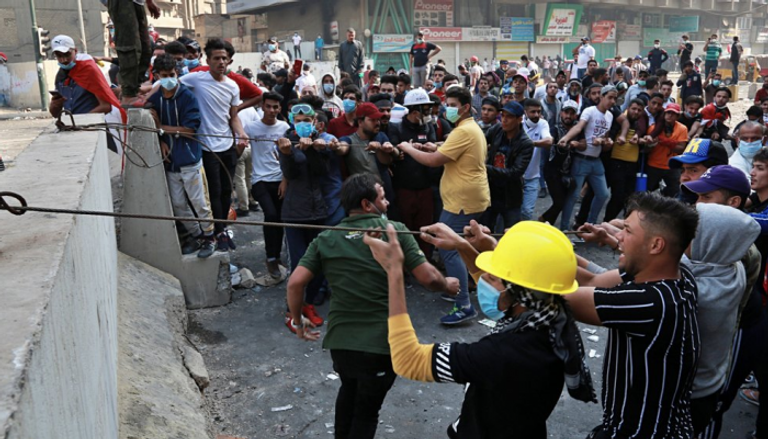 عراقيون يحاولون رفع أحد الحواجز في بغداد