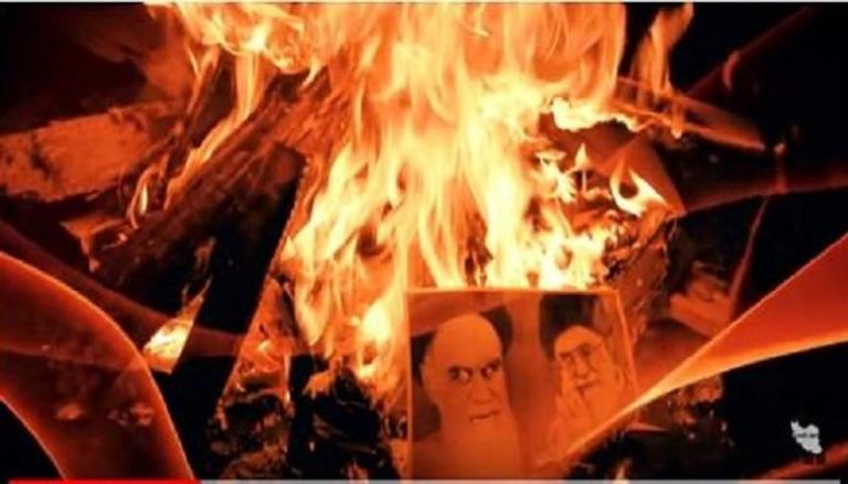 متظاهرون إيرانيون يحرقون صور مرشد إيران السابق والحالي- أرشيفية