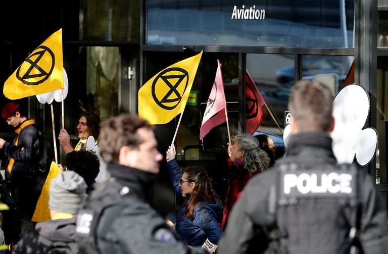 النشطاء يجلسون أمام مبنى مدرج الطائرات الخاصة بمطار جنيف