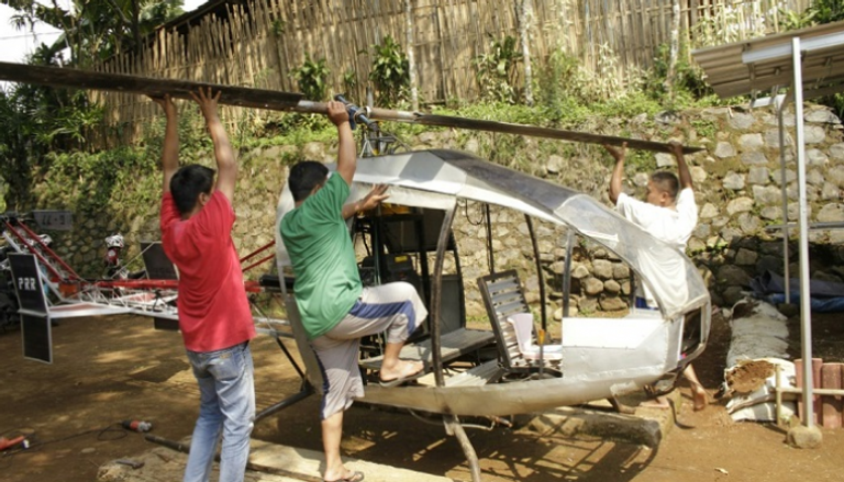 جنيدي (إلى اليمين) يعمل على طائرة الهليكوبتر بسوكابومي الإندونيسية