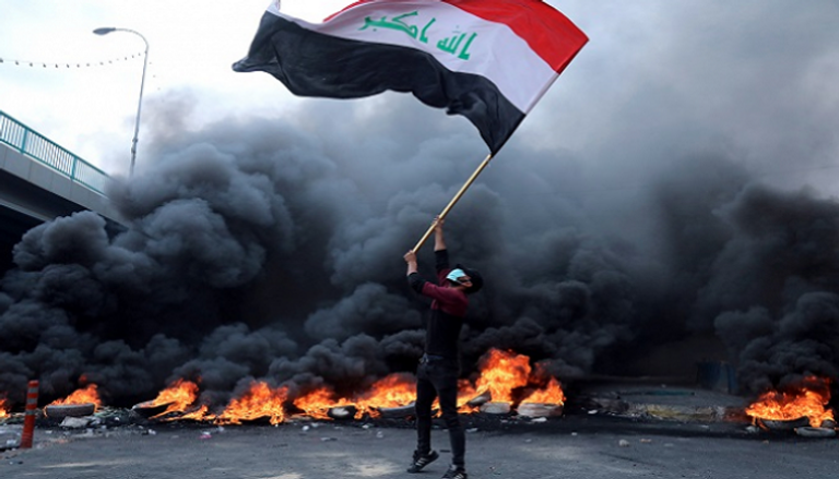 شاب عراقي يرفع علم بلاده خلال الاحتجاجات - أرشيفية