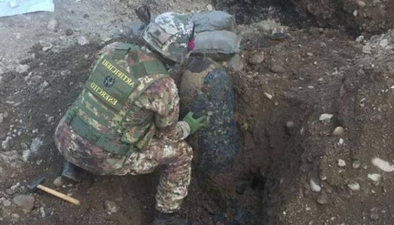 جندي يحاول تنظيف التربة بجوار القنبلة 