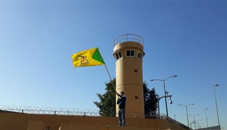 أحد عناصر حزب الله العراقي يعتلي سور السفارة الأمريكية