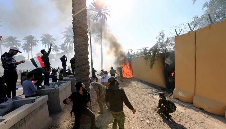 عناصر مليشيا حزب الله العراقية يضرمون النيران بسور السفارة الأمريكية ببغداد