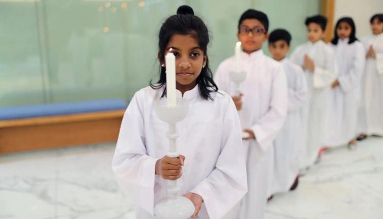 أطفال يحملون الشموع في كنيسة القديس فرنسيس الأسيزي بدبي